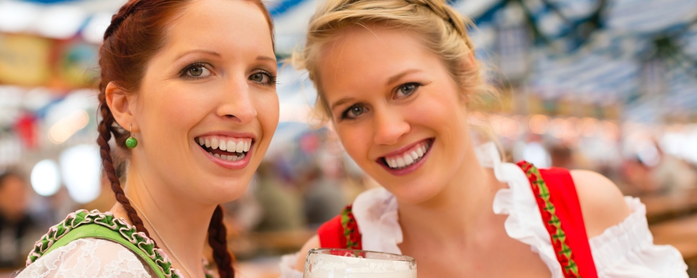 Junge Frauen feiern auf dem Oktoberfest in Bayern zur Musik einer Stimmungsband